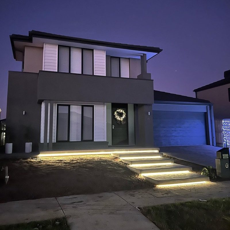 Front steps lit by LED strips under each tread of a two-storey home at dusk