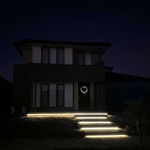 Two-storey house at night with LED strips glowing under the front steps
